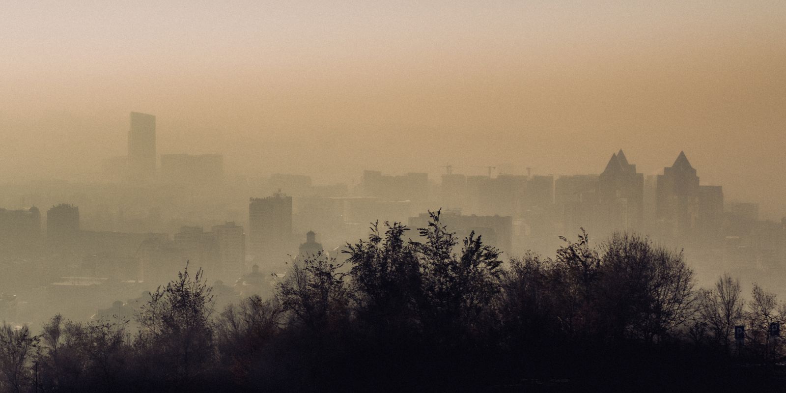 Atmospheric view of Almaty city skyline enveloped in fog and smog.